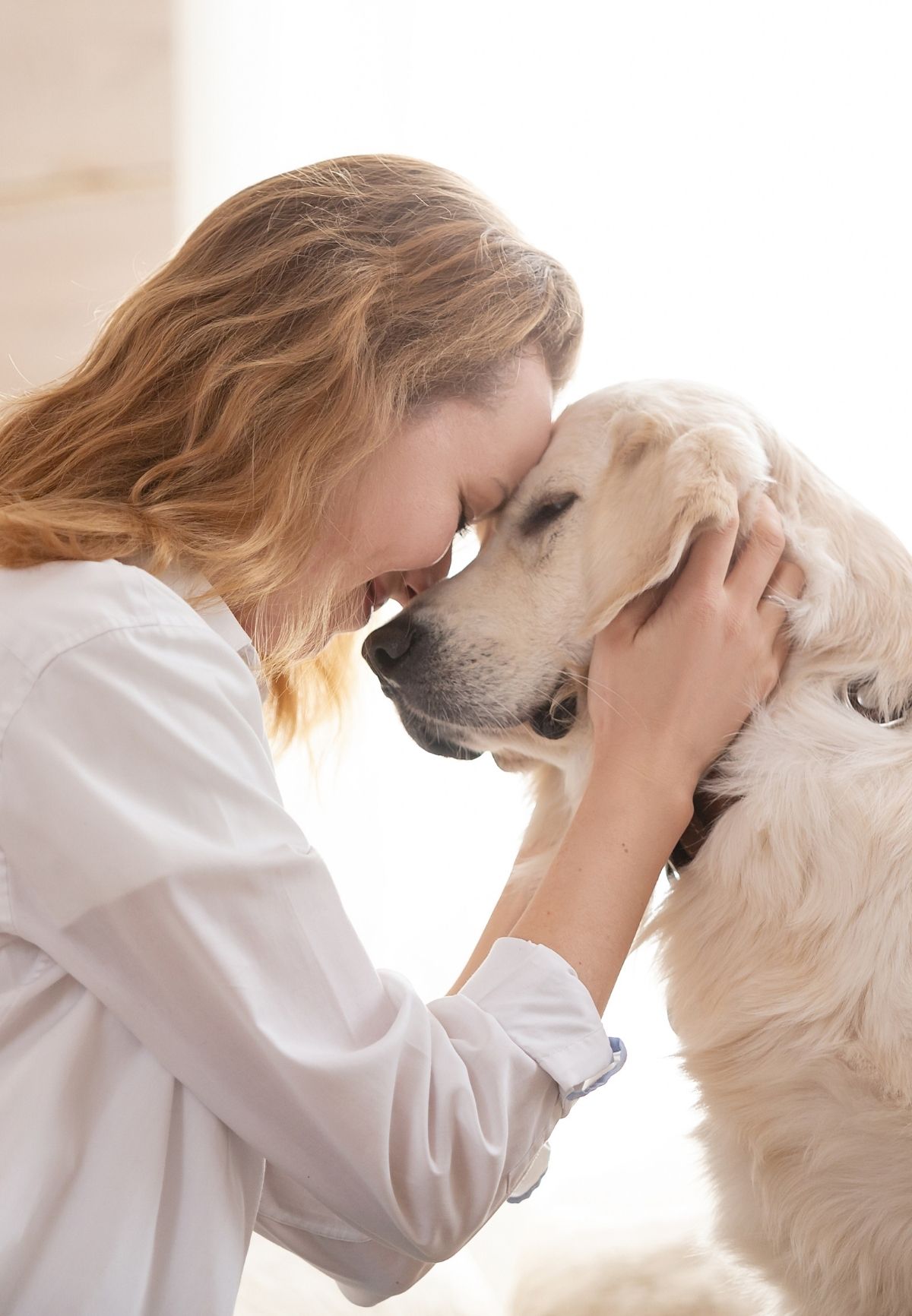 Woman embracing her white golden retriever